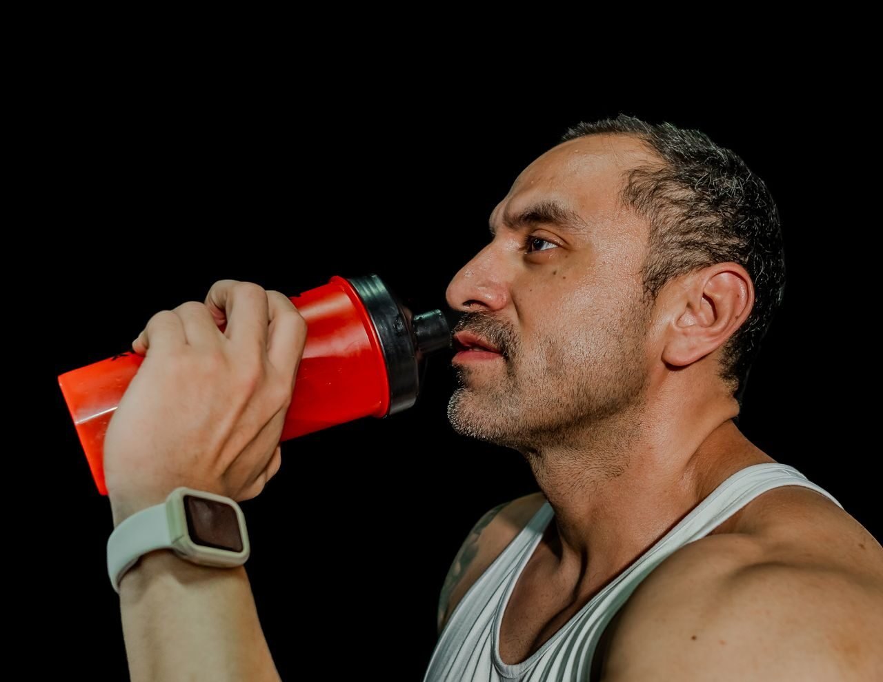 man drinking from a shaker bottle at the gym