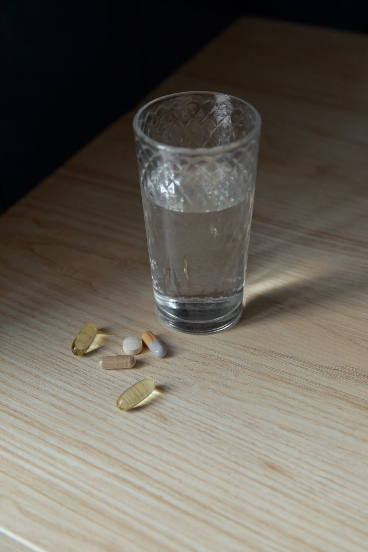 glass of water next to supplement capsules