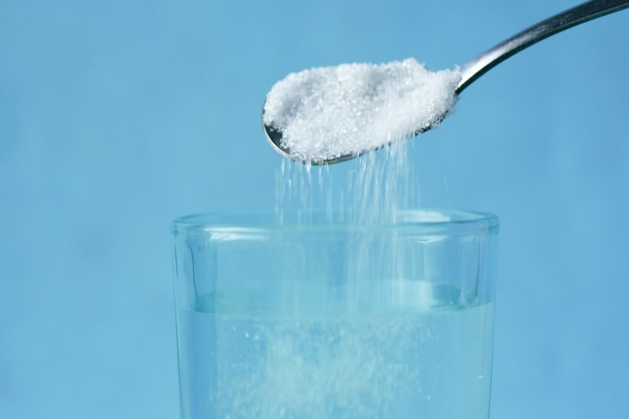 white powder dissolving in a glass of water