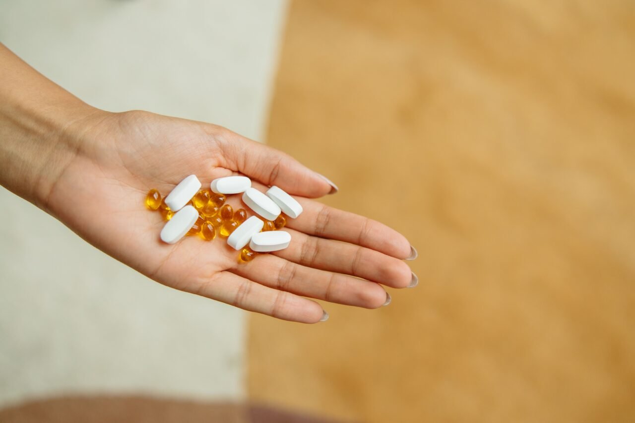 hand holding vitamin D3 and K2 softgel capsules in warm light