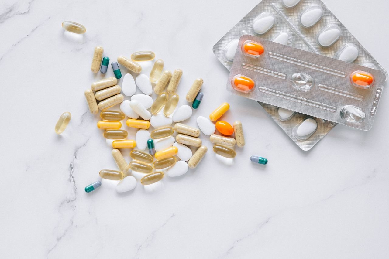Assorted supplement capsules and blister packs on a white marble surface