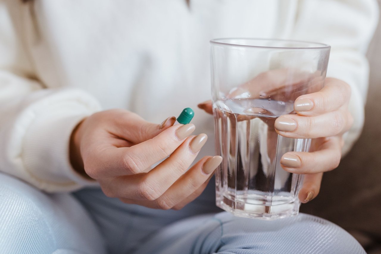 taking a daily supplement capsule with water