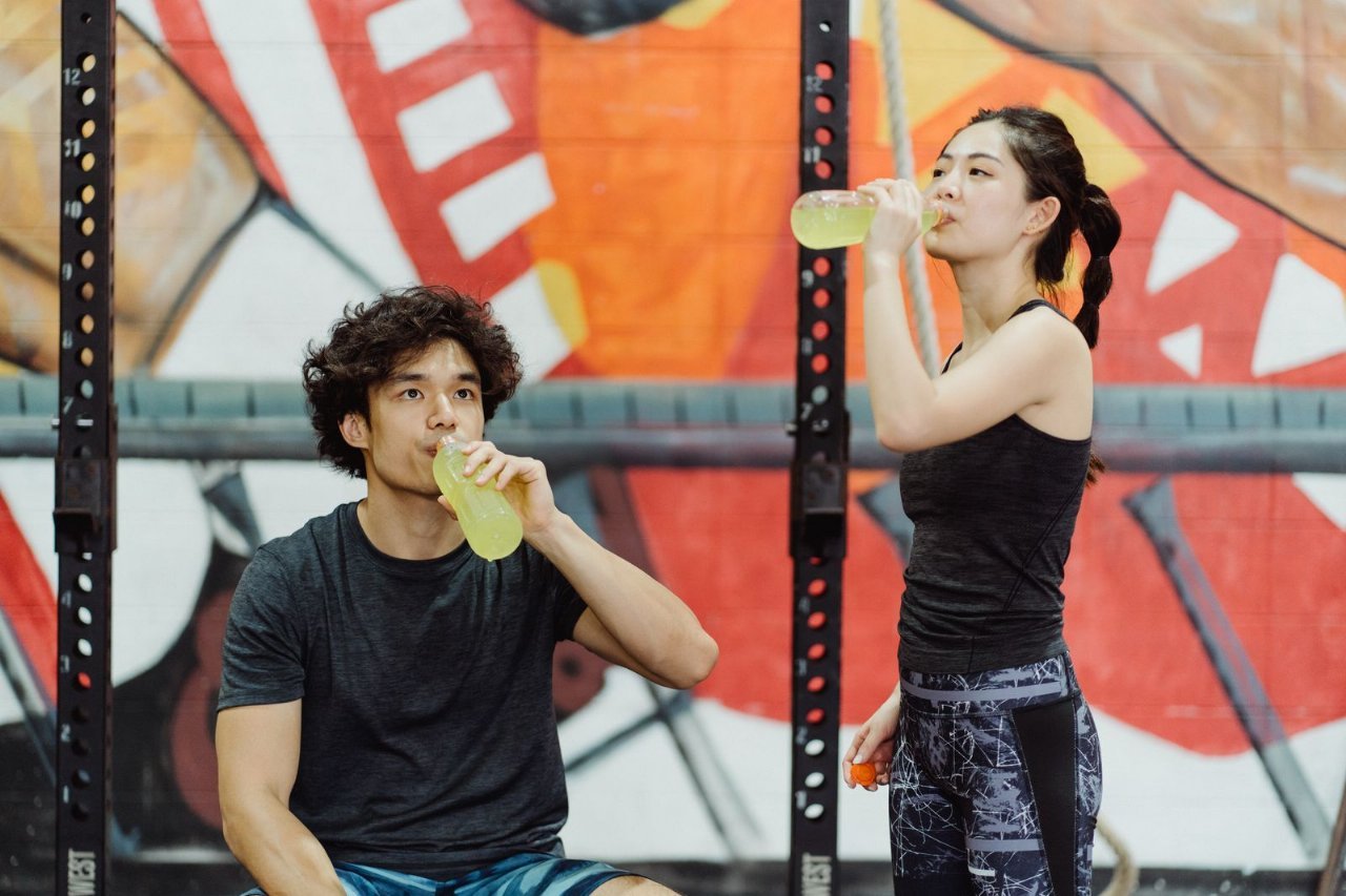 two people drinking sports drinks in a gym