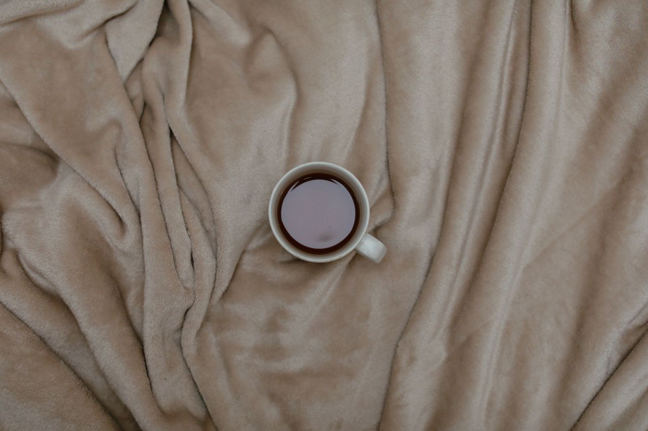 cup of tea on a soft beige blanket seen from above